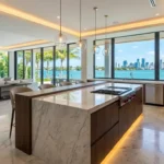 Kitchen Luxury waterfront kitchen with large marble island, custom wood cabinetry, and panoramic bay views in South Florida