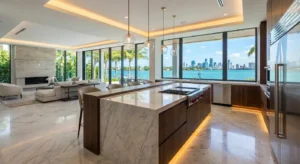 Luxury waterfront kitchen with large marble island, custom wood cabinetry, and panoramic bay views in South Florida