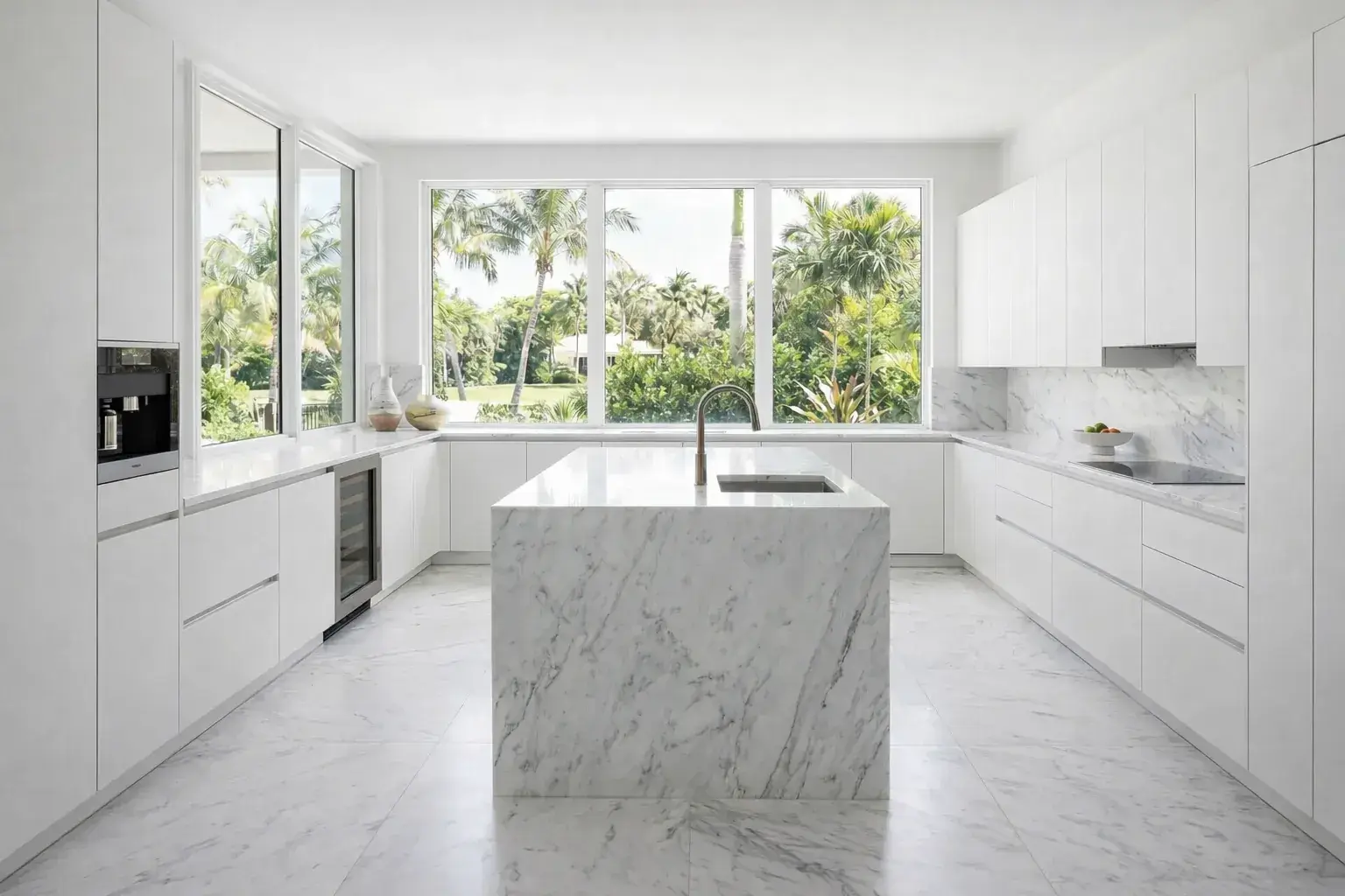 Kitchen Bright Palm Beach kitchen featuring sleek white cabinets, marble countertops and backsplash, integrated appliances, and expansive garden views.