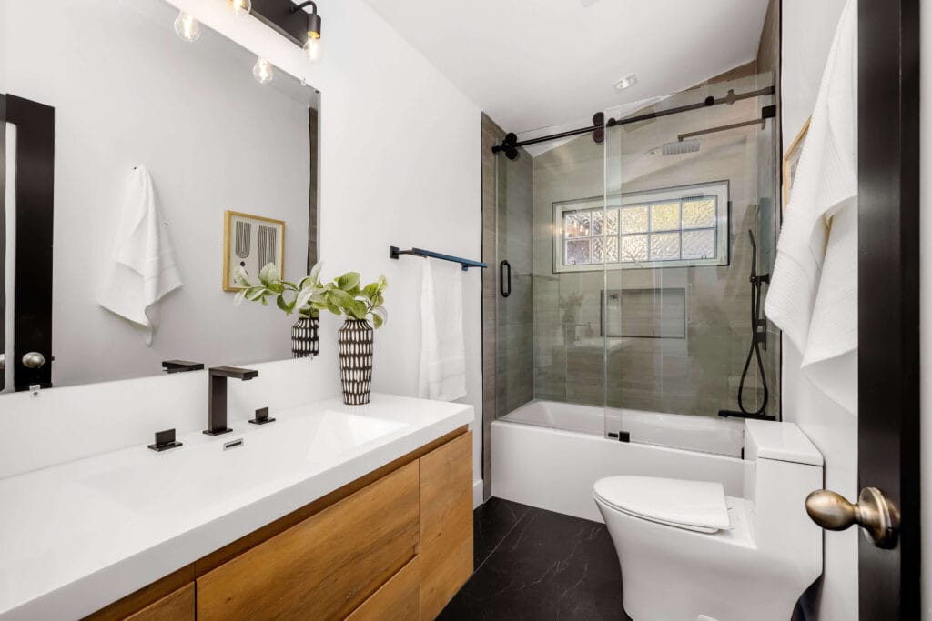 Standard bathroom with neutral tile flooring, white vanity, and simple mirror design