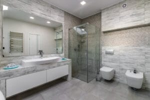 bathroom with a shower cabin, a large mirror and a chrome heater or a radiator of a towel against a white wall. loft style in a new apartment