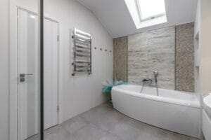 bathroom with a shower cabin, a large mirror and a chrome heater or a radiator of a towel against a white wall. loft style in a new apartment