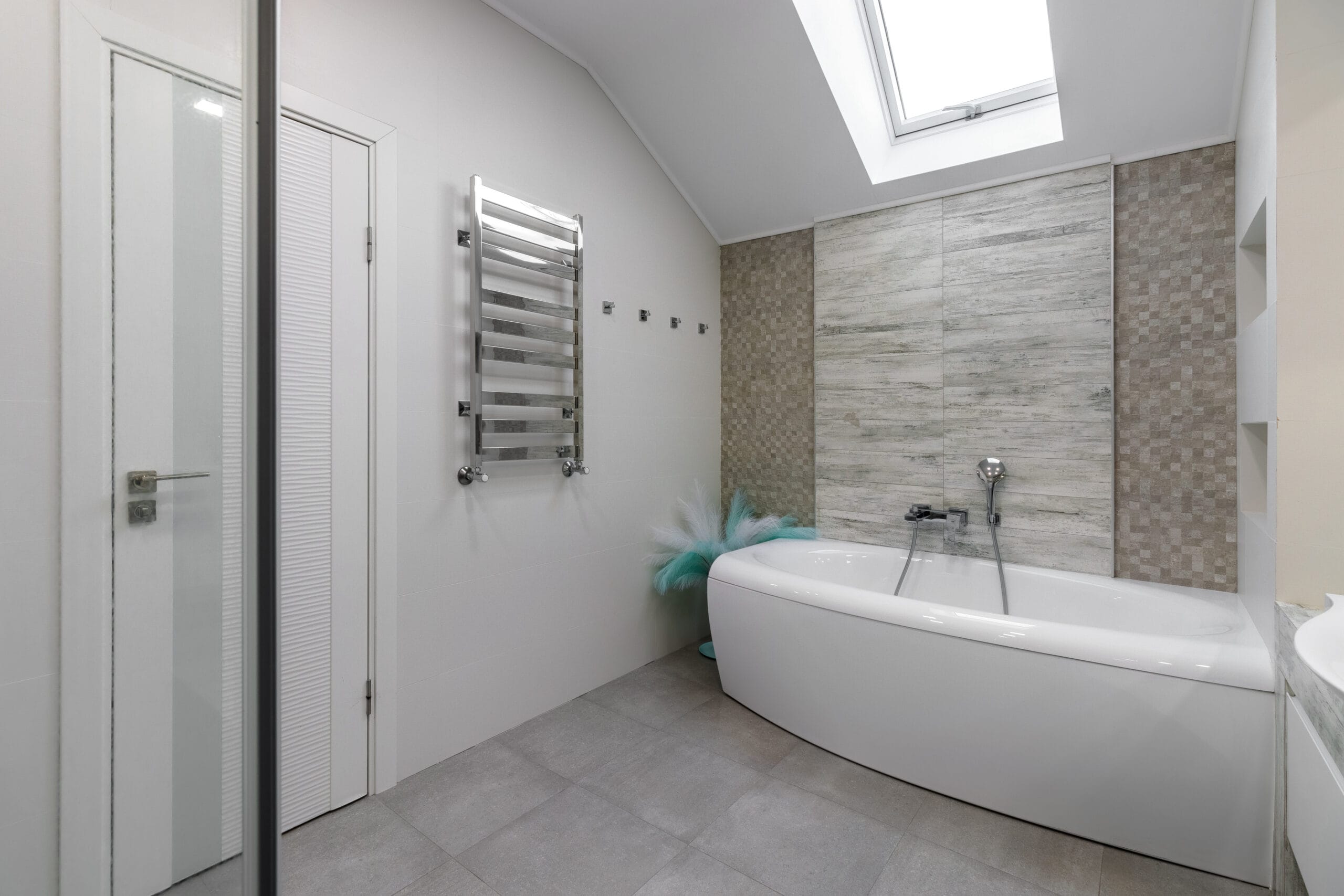 bathroom with a shower cabin, a large mirror and a chrome heater or a radiator of a towel against a white wall. loft style in a new apartment